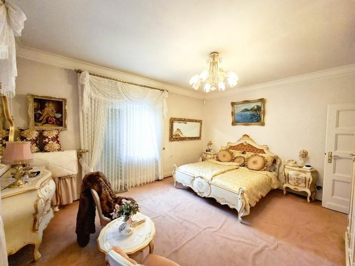 Großes Schlafzimmer mit seitlichem Balkon und angrenzendem Badezimmer