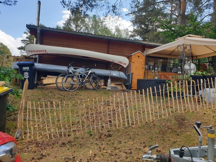 Ruhig, sicher und abseits von einer Stadt: Holzhaus Luxuslage im Wald eingebettet zwischen 3 Seen – Seitenansicht