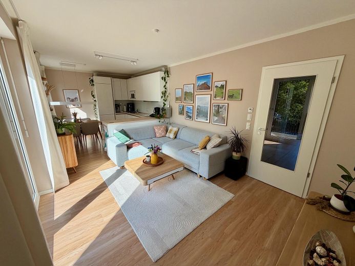 Sin comisión: Moderno apartamento de 4 habitaciones con balcón orientado al oeste y plaza de garaje subterránea con posibilidad de carga – Wohnzimmer