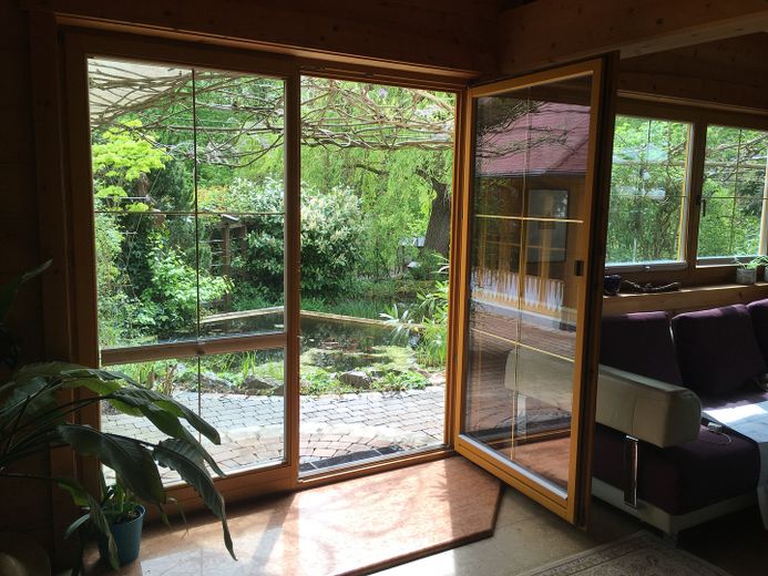 Am Waldrand gelegenes Einfamilienhaus mit ELW und parkähnlichem Garten – Blick Wohnzimmer in Garten