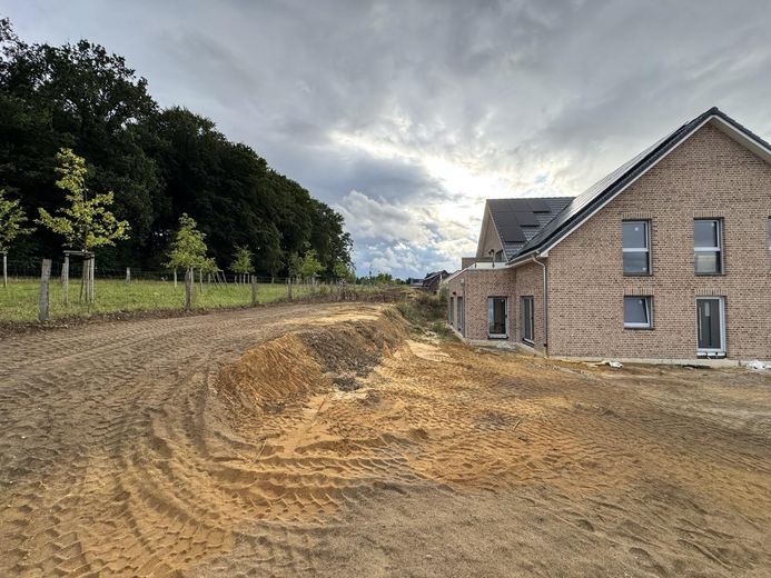 Hochwertige 3-Zimmer-Gartenwohnung mit Südterrasse, Designküche & Blick ins Grüne – Hausansicht mit Grünblick