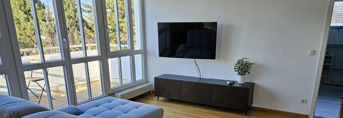 Möblierte 2-Zimmer-Wohnung mit Balkon, TG-Stellplatz und WLAN – ideal für Expats – Wohnzimmer mit Schlafcouch