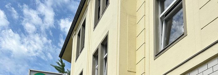 Negozio compatto a Düsseldorf-Rath – fermata dell’autobus proprio davanti alla porta – Seitenblick: Bushaltestelle