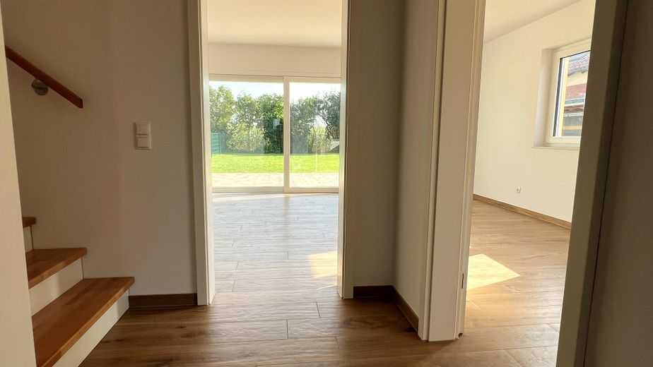 Ruhe mit Blick über Felder: Exklusives wohngesundes Plusenergie-Doppelhaus, S-Bahn fußläufig – Flur mit Blick ins Wohnzimmer
