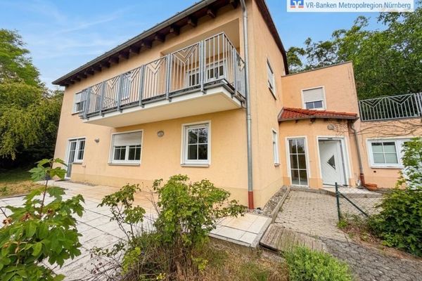 Casa unifamiliare su un pendio con panorama e terreni boschivi confinanti.