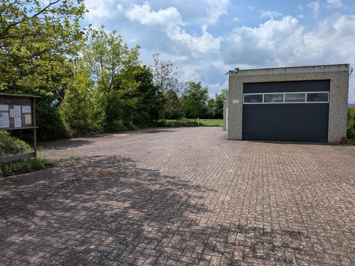 Bedrijfsterrein (splitsing mogelijk) met grote garages en woonmogelijkheid aan de rand van het veld – Ansicht von der Straße