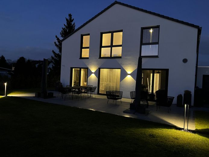 Modernes Einfamilienhaus mit großem Garten – Gartenansicht am Abend