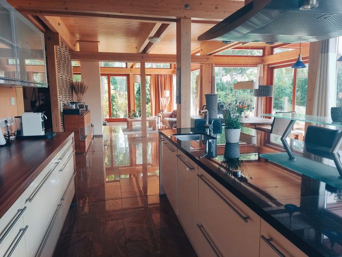 Lichtdurchflutete, energieeffiziente Villa aus Holz, Glas und Stein – Blick aus der offenen Küche