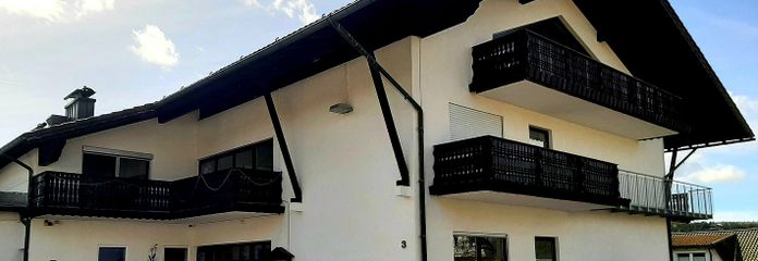 2x 1 Zi-Appartement & 3-Zi DG Wohnung mit Panoramablick, Balkon u. Küchenzeile u. 2 Duschbädern – Blick vom Parkplatz aufs Haus