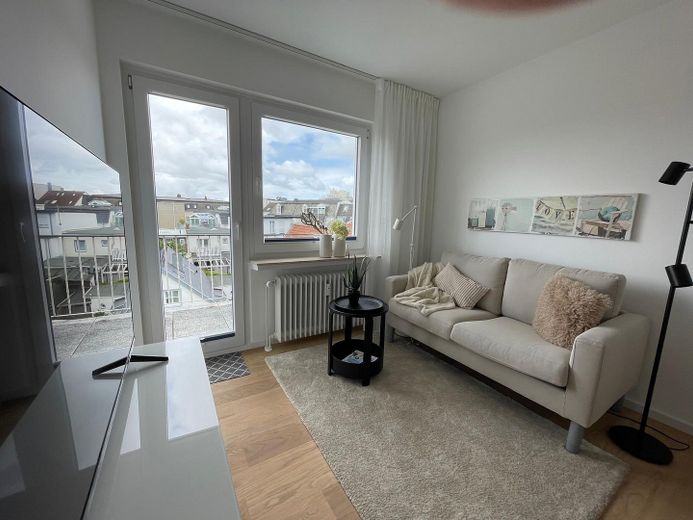 Above the rooftops of Norderney: Stylish 2-room apartment with sunny balcony – Wohnzimmer mit Balkonzugang