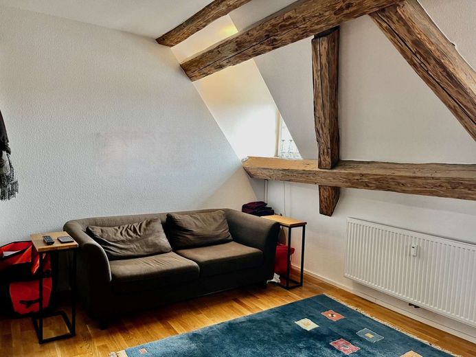 Wo Geschichte auf Gemütlichkeit trifft: Ihr neues Zuhause unterm Dach – Wohnzimmer