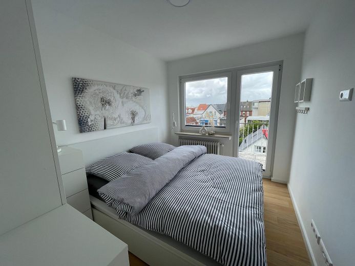 Above the rooftops of Norderney: Stylish 2-room apartment with sunny balcony – Schlafzimmer mit Balkonzugang
