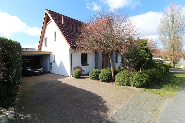 Exquisites Einfamilienhaus in neuwertigem Zustand mit PV-Anlage,Carport und idyllischer Gartenanlage – Giebelansicht mit Carport