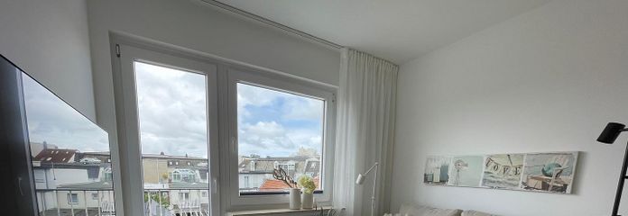 Above the rooftops of Norderney: Stylish 2-room apartment with sunny balcony – Wohnzimmer mit Balkonzugang