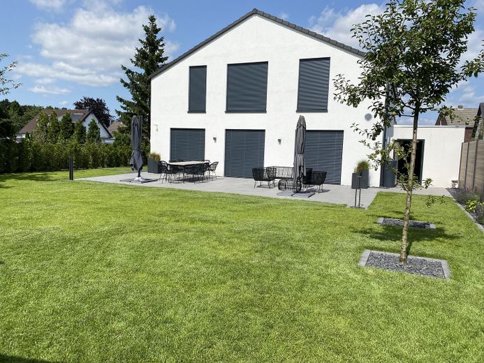 Modernes Einfamilienhaus mit großem Garten – Gartenansicht mit Terrasse